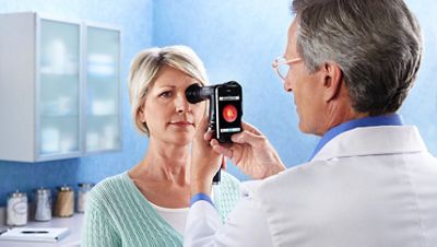 A physician utilizes digital fundus photography on a patient.