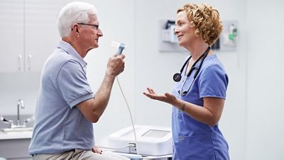 A clinician talks to a patient with the Connex Integrated Wall System visible in the background.