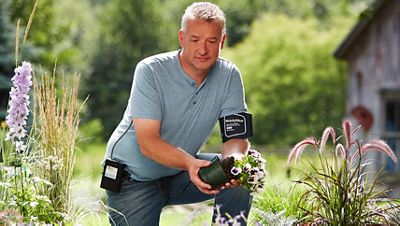 A person wearing the Welch Allyn ABPM 7100 while gardening.