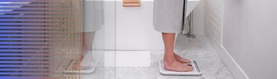 A person weighs themself on a Welch Allyn Home™ Scale in their bathroom.