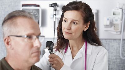 A doctor is about to perform a physical exam with tools from the integrated wall system in the exam room.