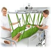Two clinicians use a FlexoStretch Lift Stretcher to lift a patient above a hospital bed