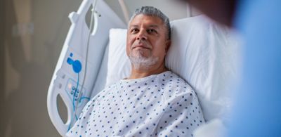 A patient sits comfortably in a CENTRELLA Smart+ bed in a hospital med-surg unit.