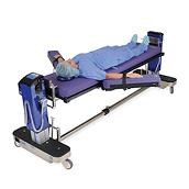 Stół Allen Advance Table — widok pod kątem z pacjentem ułożonym w pozycji leżącej na plecach z rozłożonymi ramionami