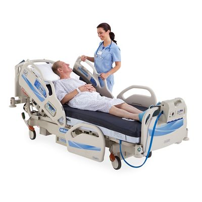 Patient reclines in bed, talking with his clinician at the bedside