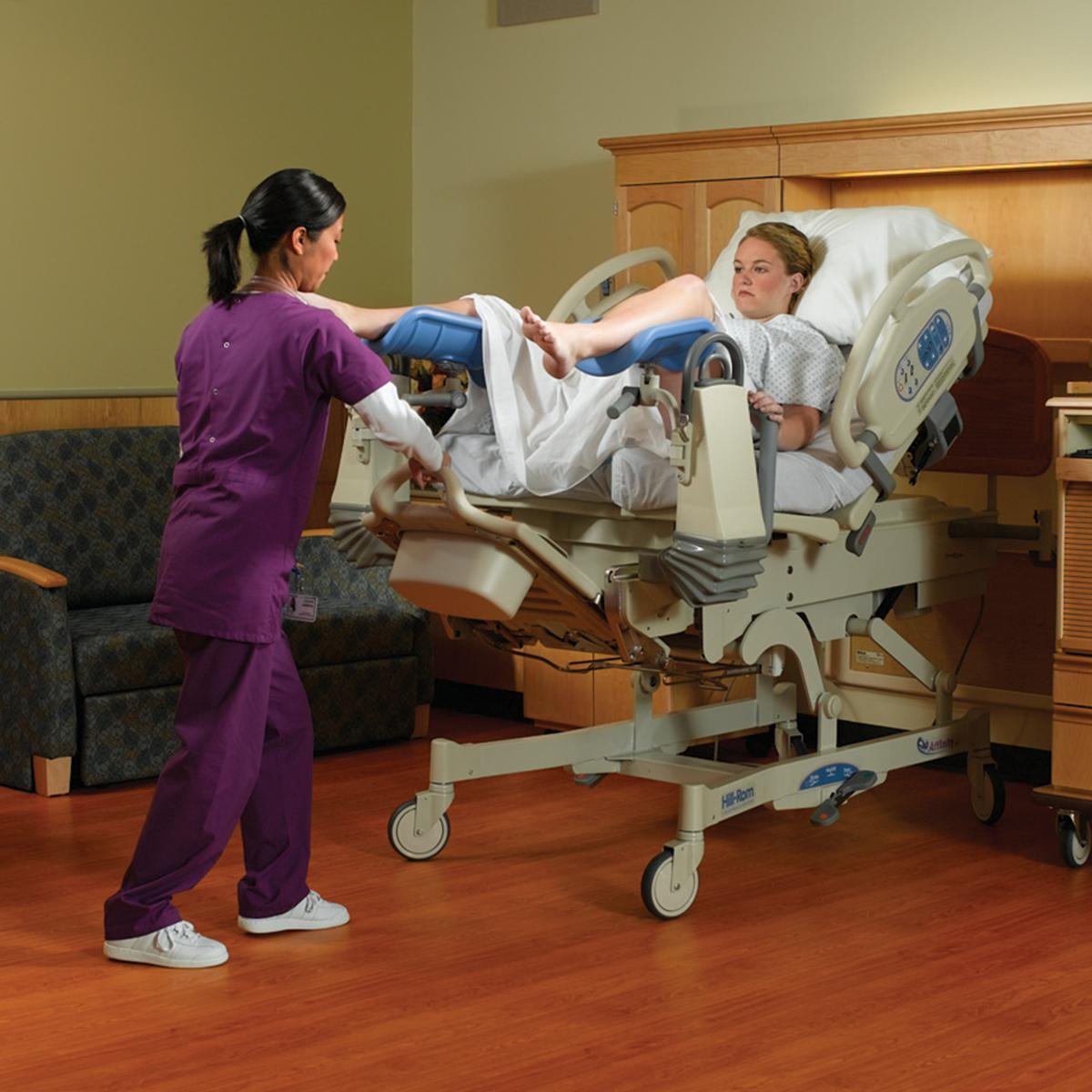 A nurse adjusts the foot section of the Affinity 4 Birthing Bed. A patient is in the bed, using the EasyGlide calf supports.