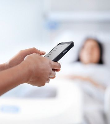A nurse using a mobile device in a hospital room.