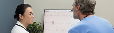 doctor sitting down with physician looking at ecg report on computer screen