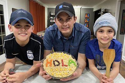 Carlos Urrea, Hillrom's Vice President of Medical Affairs & Informatics, and his two sons display a baked treat with "HOLA" written in candy