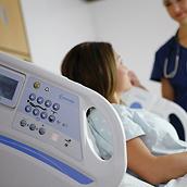 Centrella 医用电动病床控制键的近摄特写图。病床上的女性患者与病床另一侧的临床医生交谈。