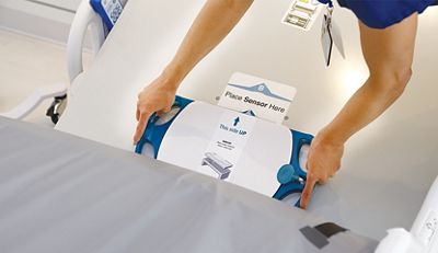 A clinician places the EarlySense sensor beneath the mattress on a Centrella Smart+ Bed