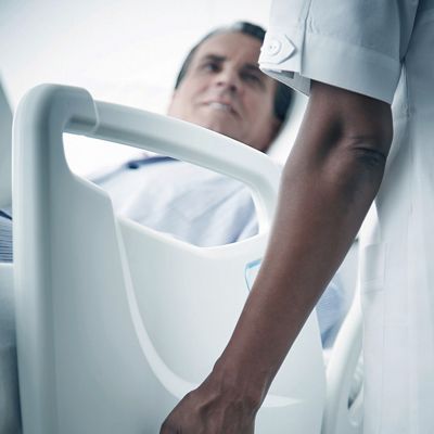 A caregiver presses a button to lower the siderail on the Centuris bed