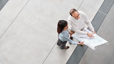 Two professionals review architectural drawings in an open indoor space