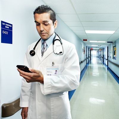 Clinician looking at smartphone in hospital hallway