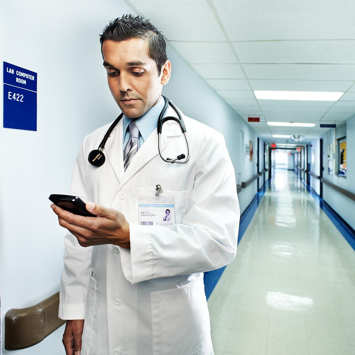 Un clinicien regarde un téléphone intelligent dans le couloir d’un hôpital