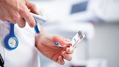 A nurse scans an ID badge.
