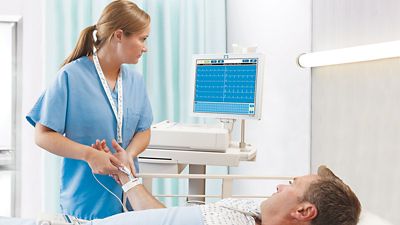 Clinician attaches leads from the ELI 380 ECG, previously branded as Welch Allyn, Mortara and Burdick, is now a Baxter diagnostic cardiology device, to a patient.