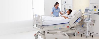 A clinician comforts a patient lying in an Envella Air Fluidized Therapy bed