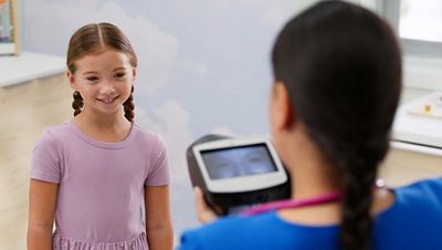 a nurse performs a vision screening on a young girl