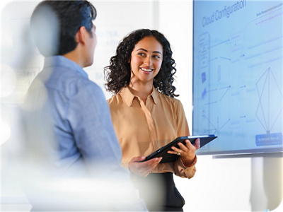 Two professionals review a digital workflow diagram on a large screen while one holds a tablet in a clinical technology setting.