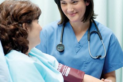 Una paciente usa un brazalete reutilizable para la presión arterial FlexiPort con su médico al lado de la cama