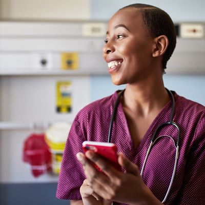 En sjuksköterska med en smarttelefon och en patient i bakgrunden