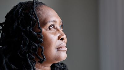 Female patient is in her home looking out a window, feeling confident that her care team is monitoring her vitals with the Hillrom Extended Care Solution while she remains at home. 