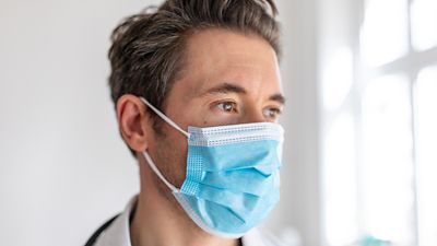 Male clinician confidently look off into the distance while wearing PPE. 
