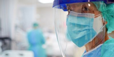 Close up view of a nurse or doctor wearing surgical mask and a face shield.
