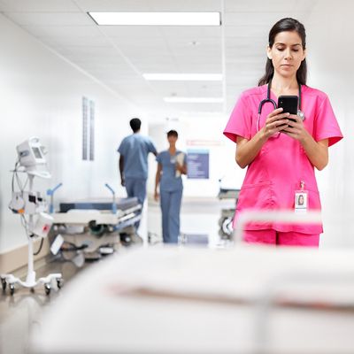 Nurse using a smartphone in a hospital hallway