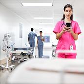 ผู้ดูแลกำลังใช้สมาร์ทโฟนบริเวณทางเดินในโรงพยาบาล