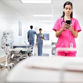 Verpleegkundige gebruikt een smartphone in de gang van een ziekenhuis