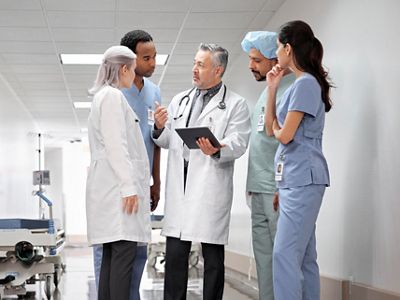 group of health professionals in hospital hallway discussing patient alert via Voalte Alert and Alarm Management