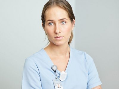 Caregiver has arms confidently crossed wearing the Hillrom Precision Locating staff badge.