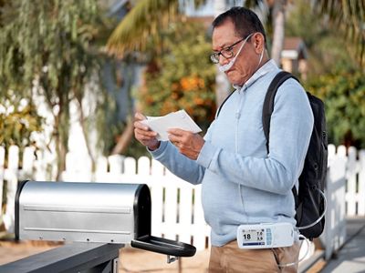 A man uses the Life2000 Ventilation System outside while getting his mail 