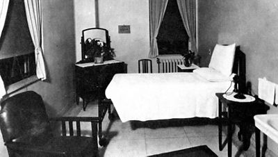 An early Hillrom wooden hospital bed is shown in a room