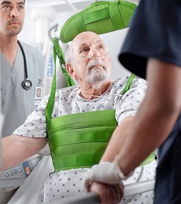 Two caregivers assisting a patient with a lift device