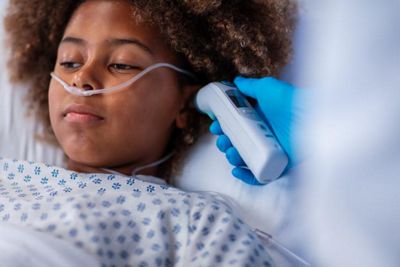 Braun ThermoScan PRO 6000 Ear Thermometer being used on a child in a hospital bed