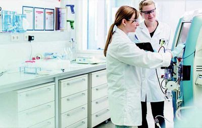 two medical professionals in a lab looking at a montor