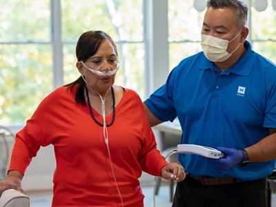 A Hillrom clinical trainer teaches a woman to use the Life2000 Ventilation System in her home 