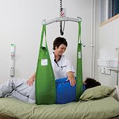 Klinikmitarbeiterin, die ein grünes MultiStrap™ Hebehilfsmittel verwendet, um einen Patienten im Bett zu drehen