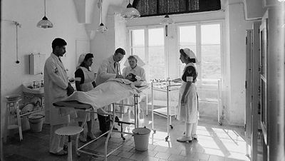 A mid-century surgical team works beneath a domed surgical light.