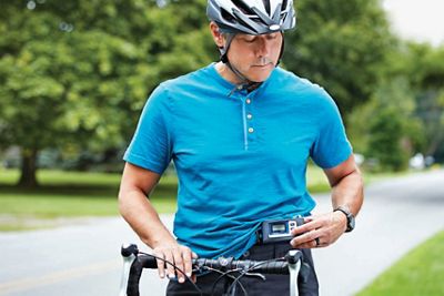 Un homme regarde son enregistreur numérique Holter tout en faisant de l'exercice à l'extérieur