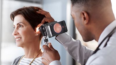 A physician uses a Welch Allyn MacroView Plus Otoscope to examine his patient's ear