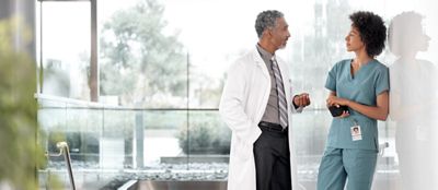 Two clinicians talk in a hospital foyer