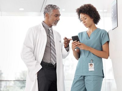 a doctor and nurse using a mobile device in hospital hallway
