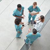 Overhead view of four nurses and a clinician conversing in a circle