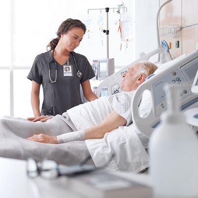 Nurse attending to a patient lying in a hospital bed