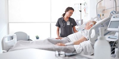 Nurse attending to a patient lying in a hospital bed