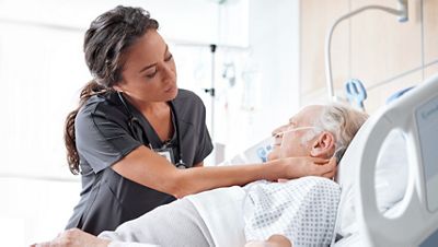 Nurse adjusts nasal cannula on elderly male patient for continuous respiratory monitoring